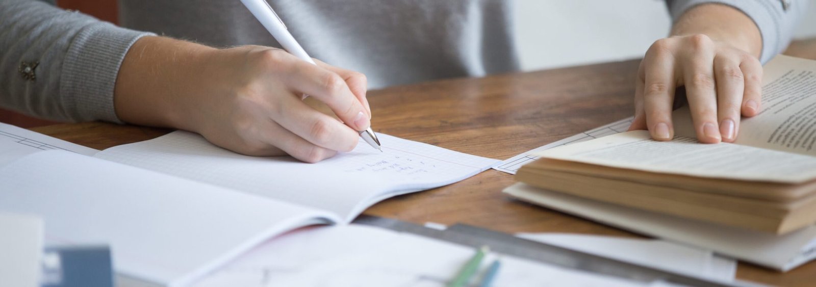 Student female hands performing a written task in a copybook with a pen, education concept photo. Close up